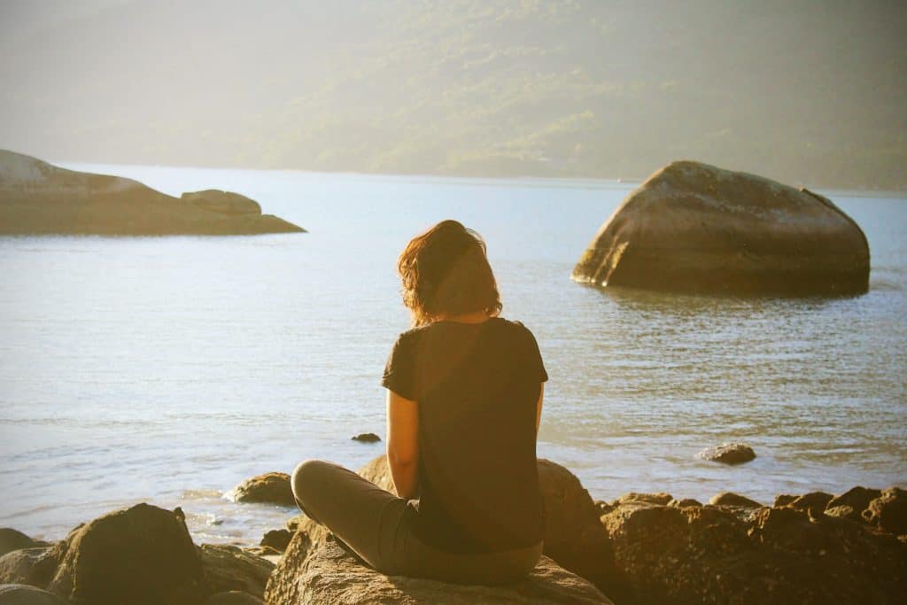 Photo by Lua Valentia person sitting near body of water during daytime
